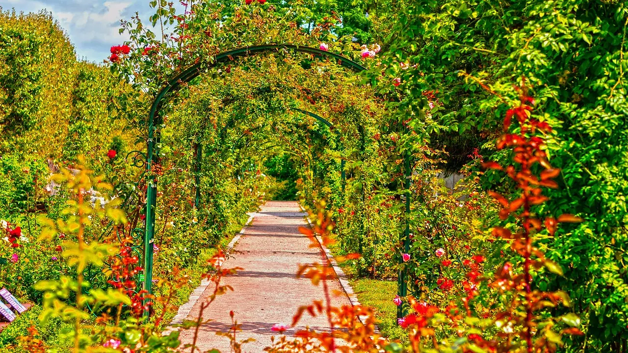 Flowered arches and planted greenery frame a public park path