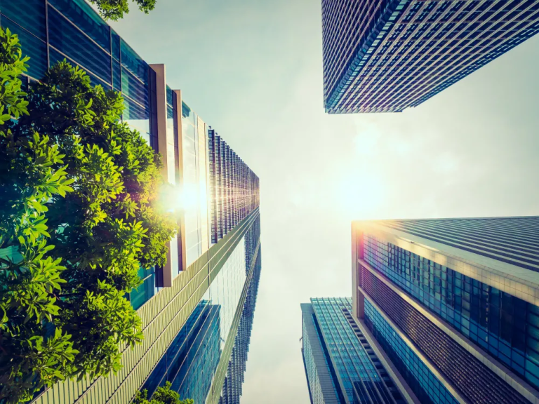 Modern city buildings with sunlight and greenery, symbolizing urban climate resilience and sustainable city planning.
