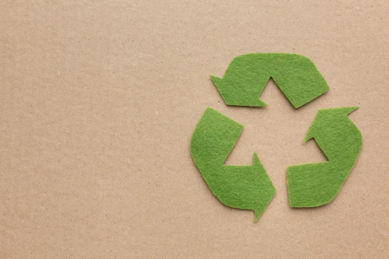 Green recycling symbol on cardboard background, representing circular economy and Extended Producer Responsibility (EPR).