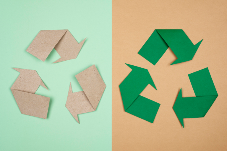 Recycling symbols made from cardboard and green paper representing circular supply chains and material reuse systems.