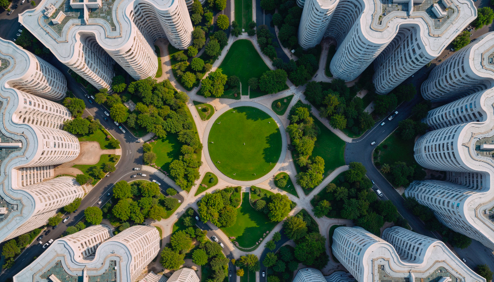 Aerial view of dense urban towers surrounding green spaces illustrating climate-sensitive design strategies for urban cooling and heat mitigation.